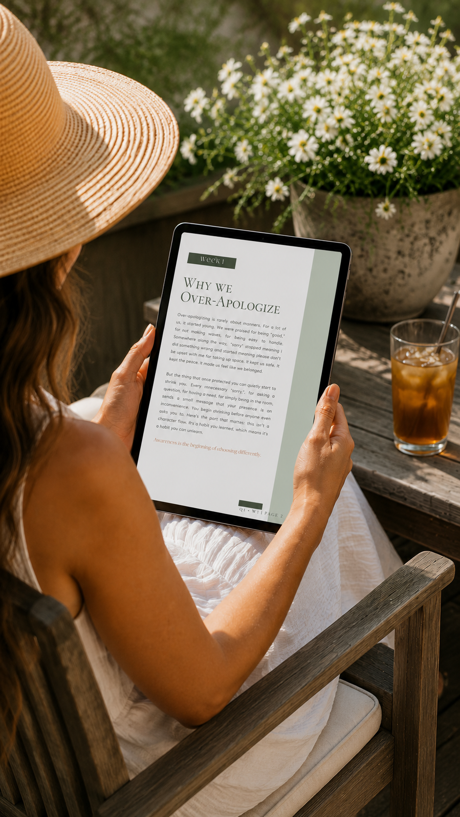 High-angle view of a woman in a sunhat sitting on a wooden patio chair, reading the Week one page of the Type C Method digital workbook on a tablet next to a glass of iced tea.